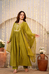 Woman in a green traditional outfit standing in front of decorative string lights.