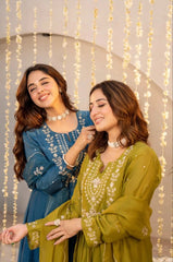 Two women in traditional outfits standing close together with a decorative string light background.