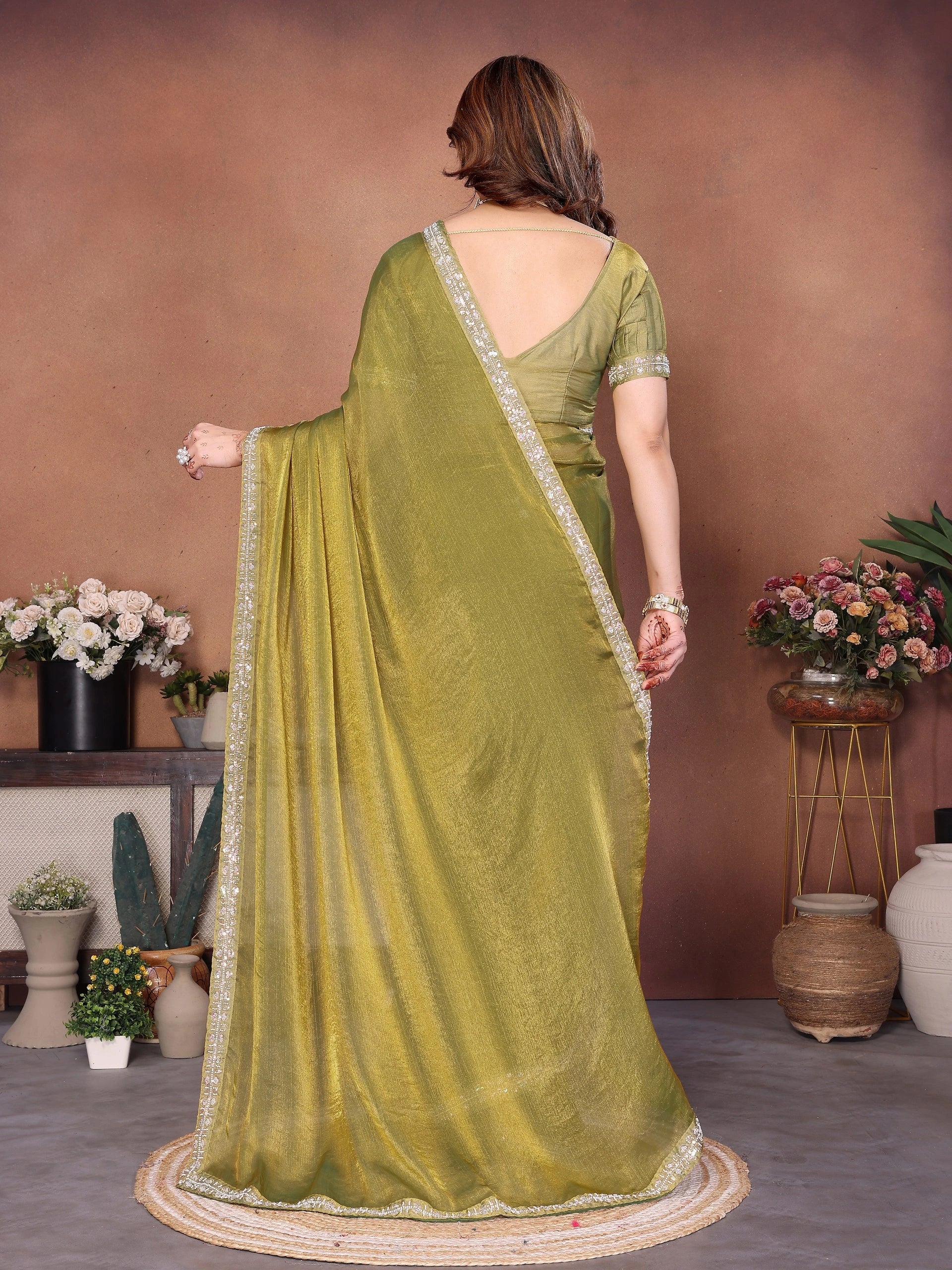 Woman wearing a green saree with a plain background