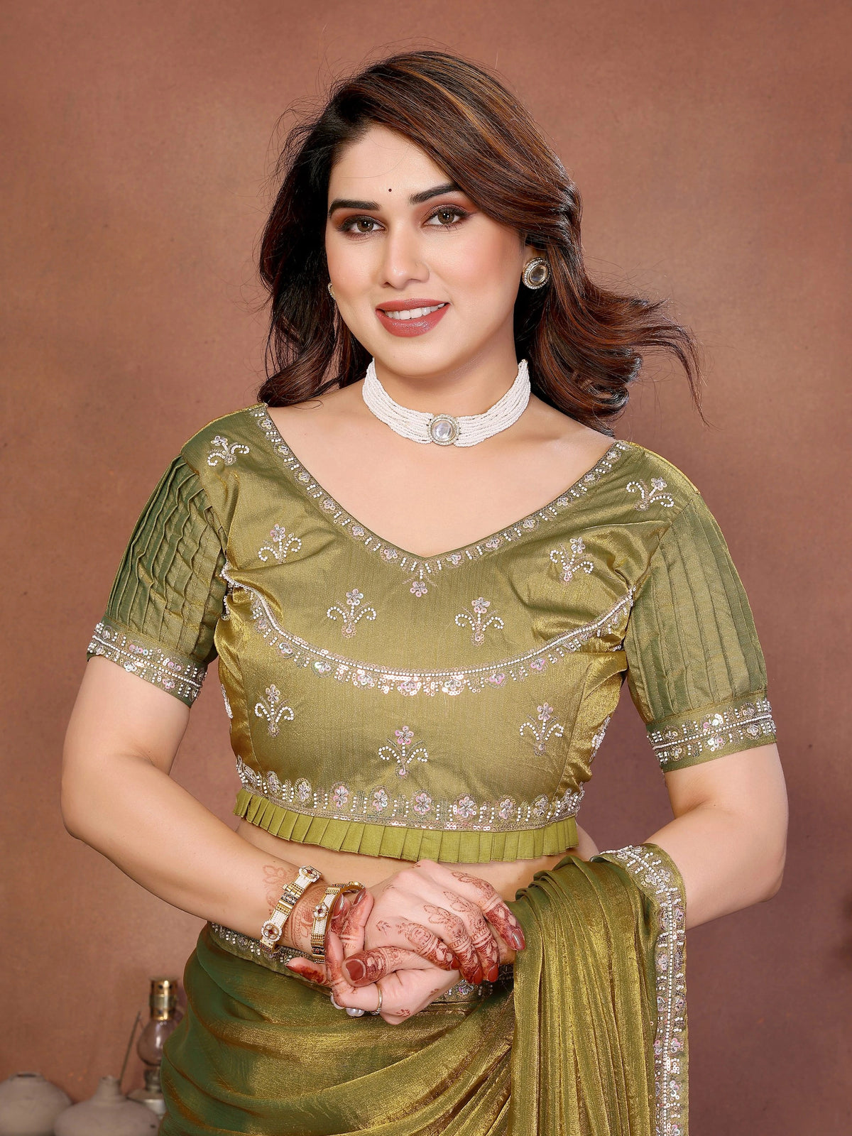Woman wearing a green traditional outfit with silver details against a brown background