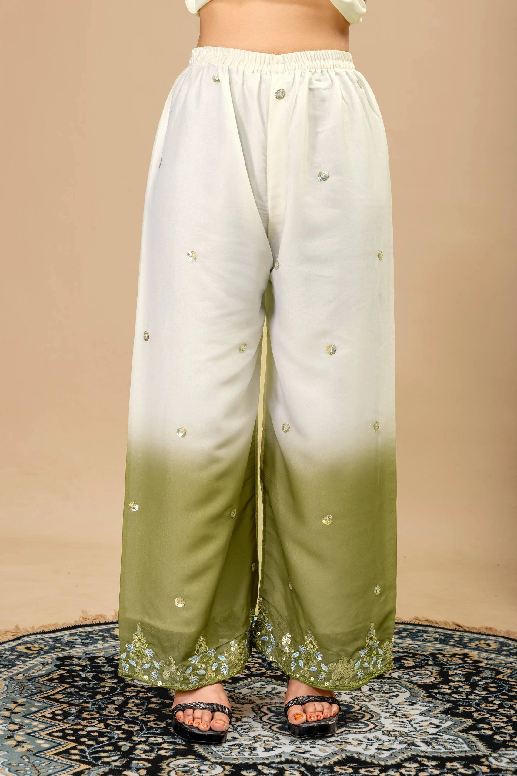 White and green gradient pants with button details on a beige background