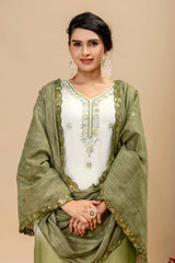 Woman wearing a green and white traditional outfit with embroidery on a beige background