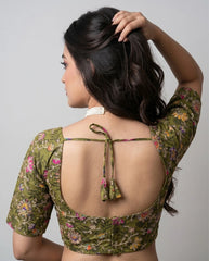 Woman wearing a floral blouse with an open back design on a gray background