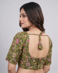 Woman wearing a green floral blouse with an open back on a white background