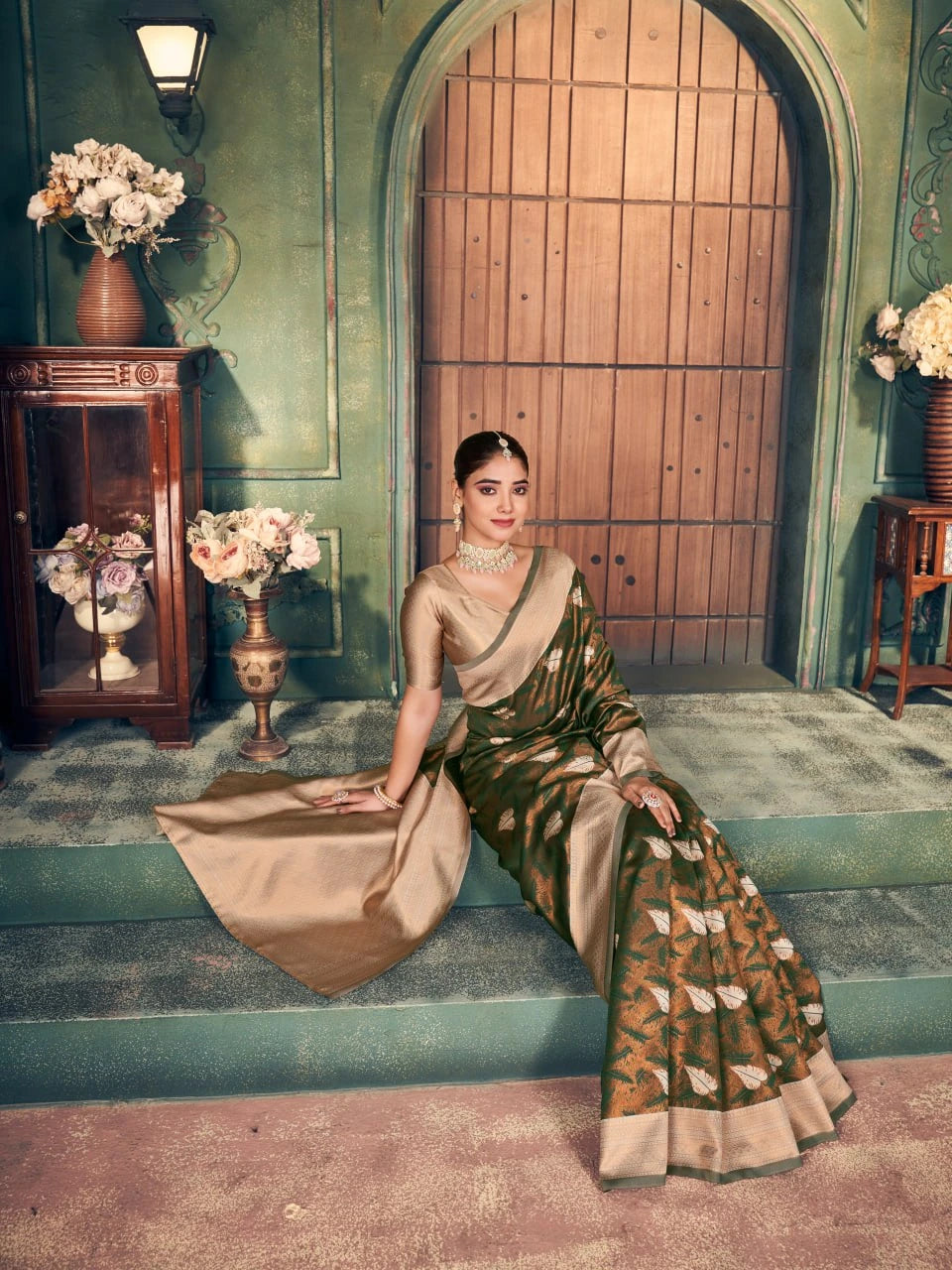 Woman in a saree sitting on steps with decorative elements in the background