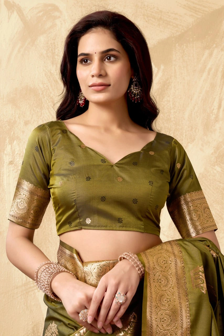 Woman wearing a green saree with gold border against a beige background