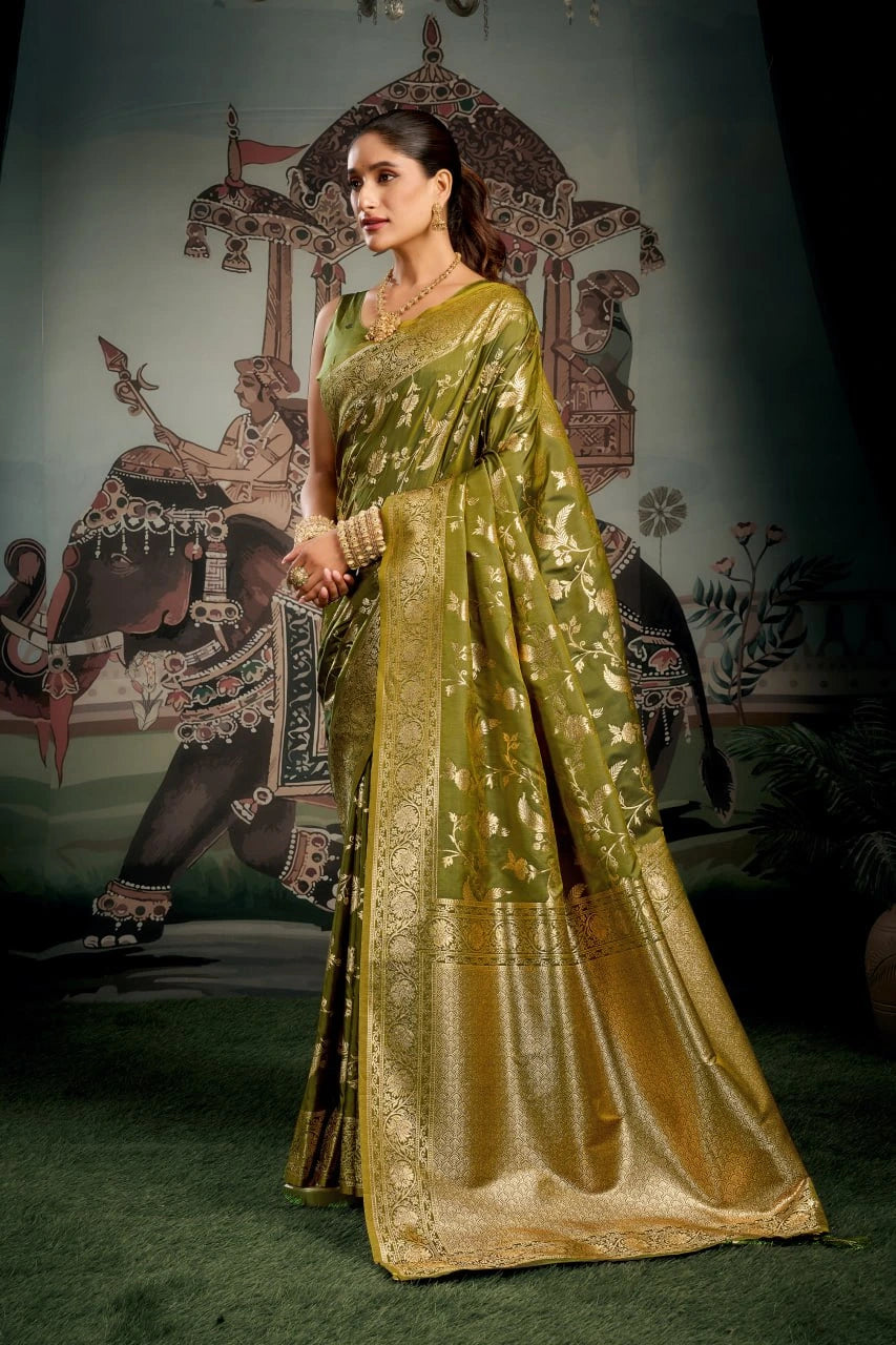 Woman in a green saree standing in front of an ornate backdrop