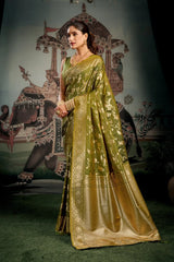 Woman in a green saree standing in front of an ornate backdrop