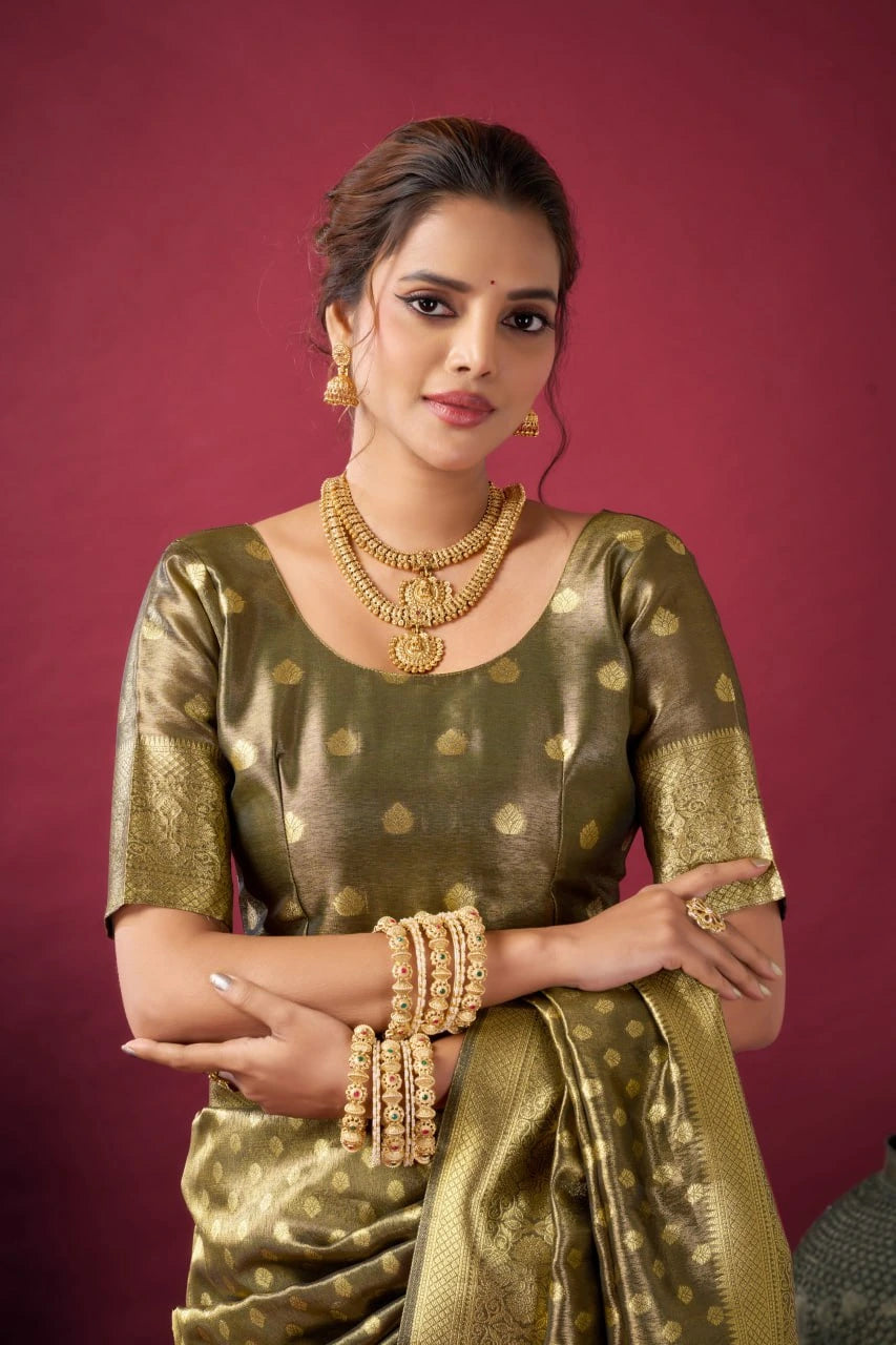 Woman in traditional gold saree with jewelry against a red background