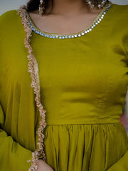 Green dress with decorative trim and jewelry on a neutral background