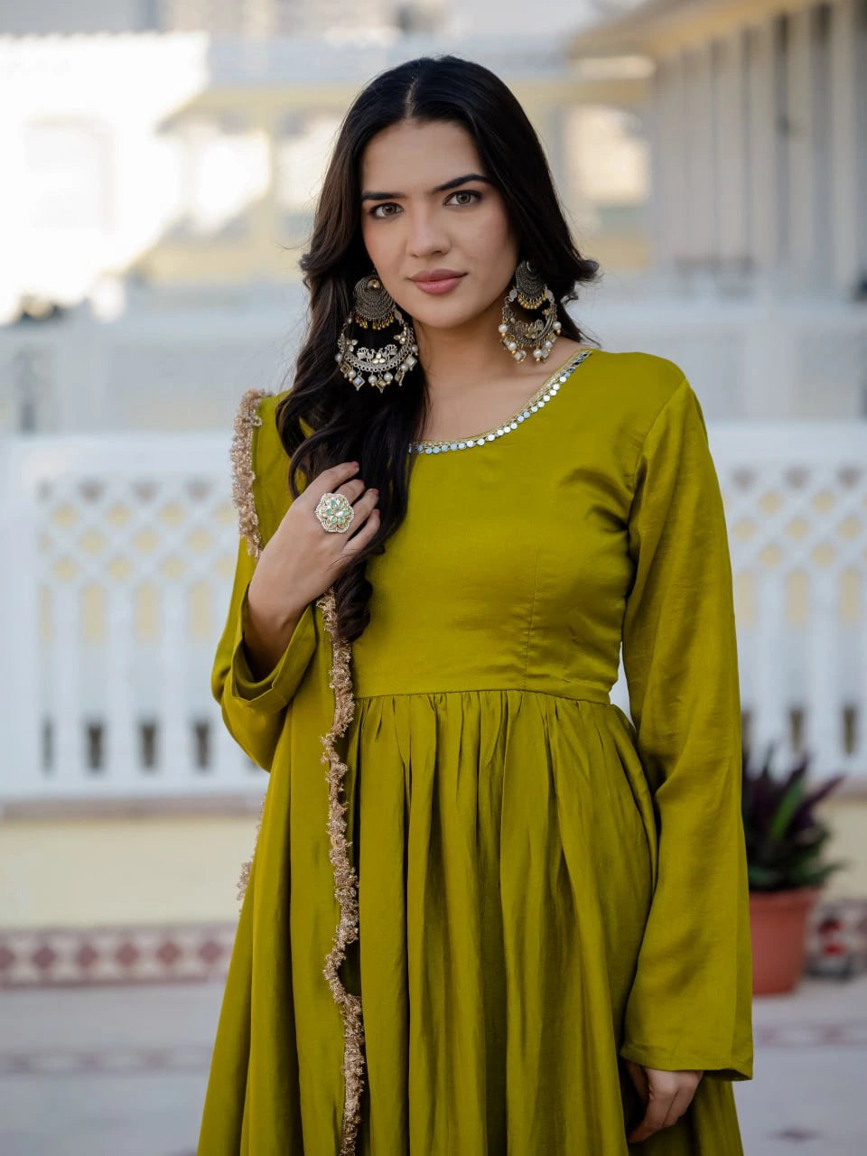 Woman wearing a green dress with long sleeves and a patterned jacket outdoors.