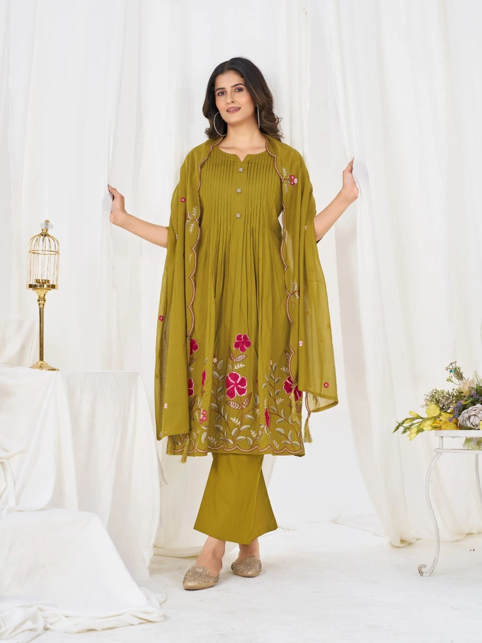 Woman wearing a green traditional outfit with floral patterns on a white background