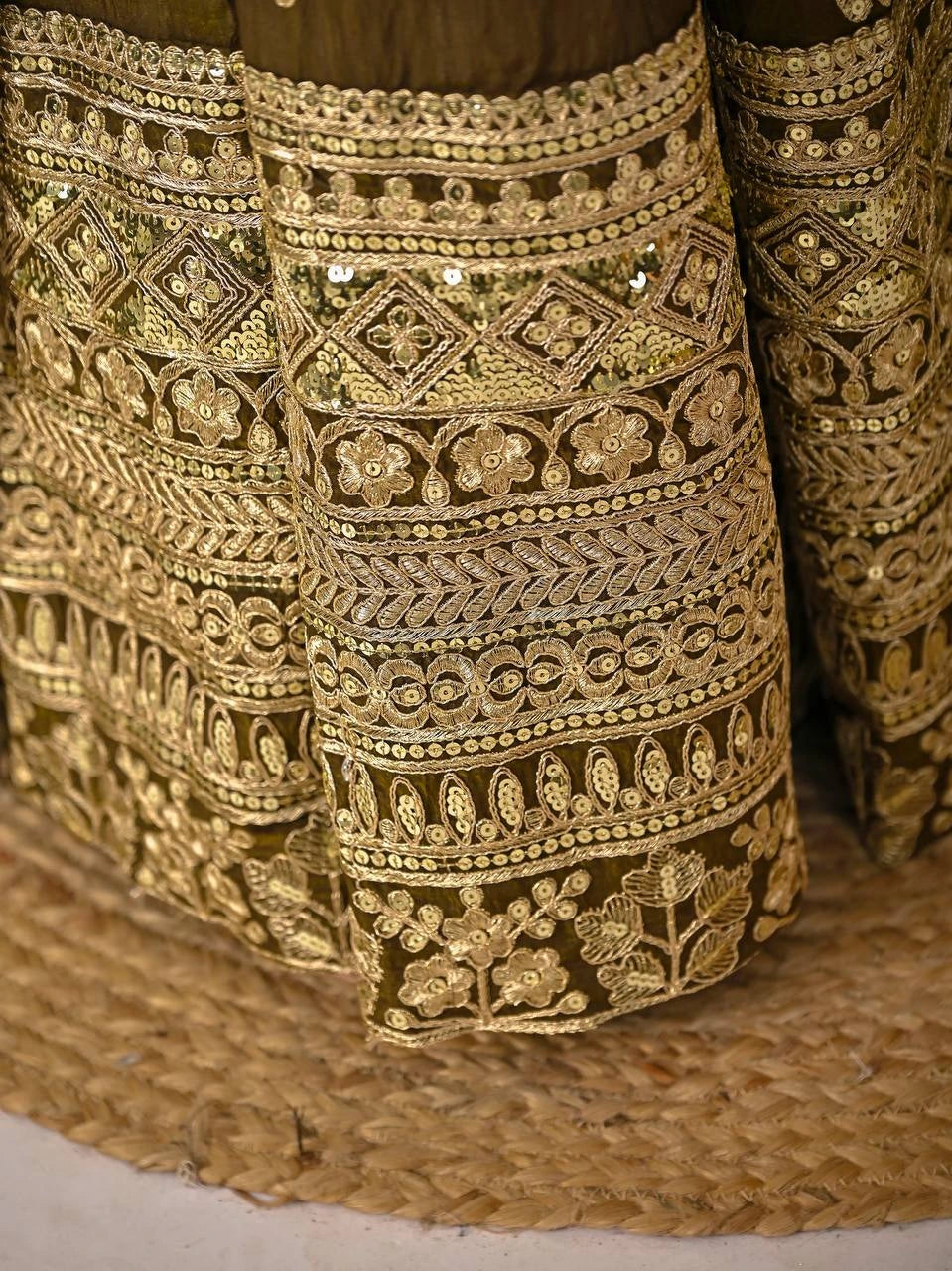 Close-up of intricately embroidered gold fabric on a textured surface