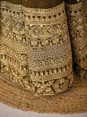 Close-up of intricately embroidered gold fabric on a textured surface