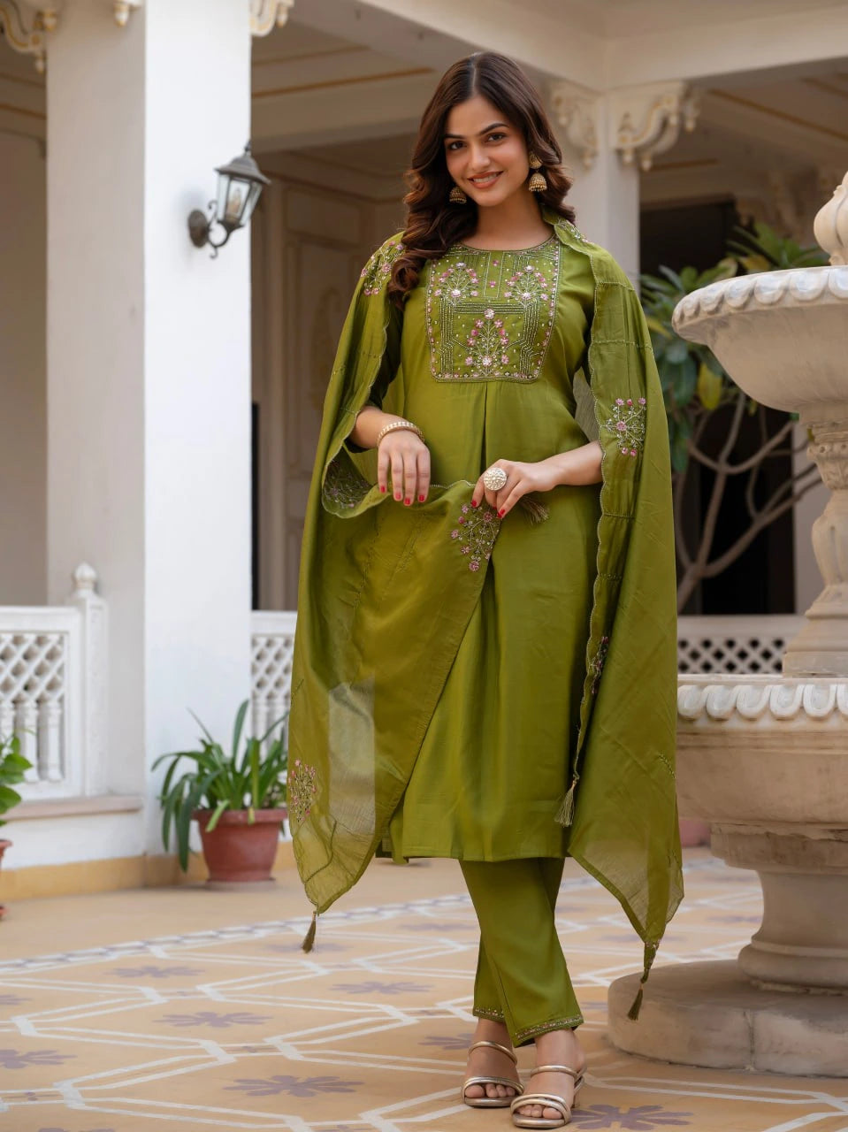 Woman in a green traditional outfit standing on a decorative patio.