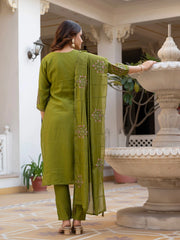 Woman in a green traditional outfit standing in an elegant indoor setting.