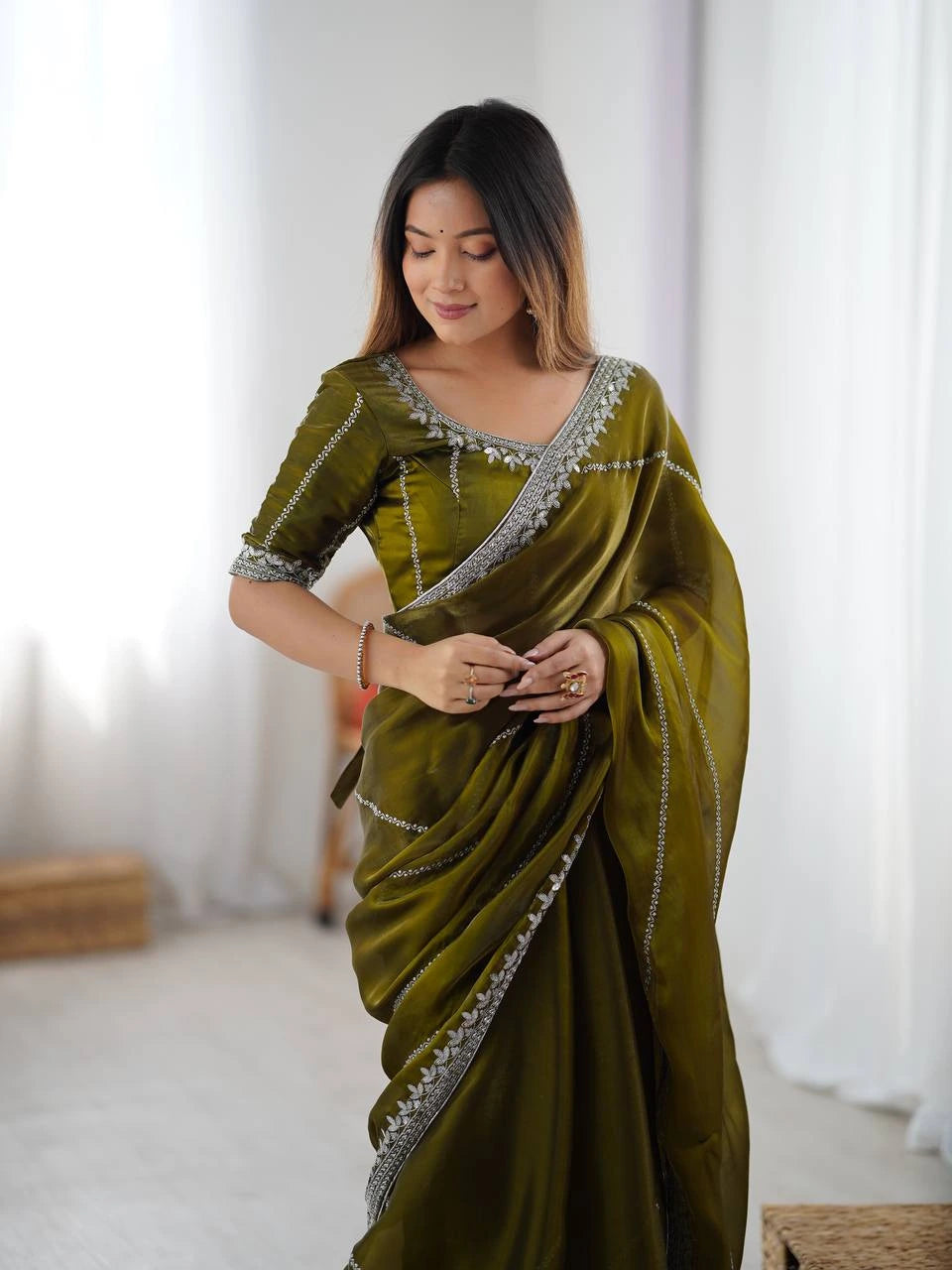 Woman wearing a green saree with silver border in a bright room