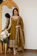 Woman in a traditional outfit standing in front of a decorative mirror with flowers.