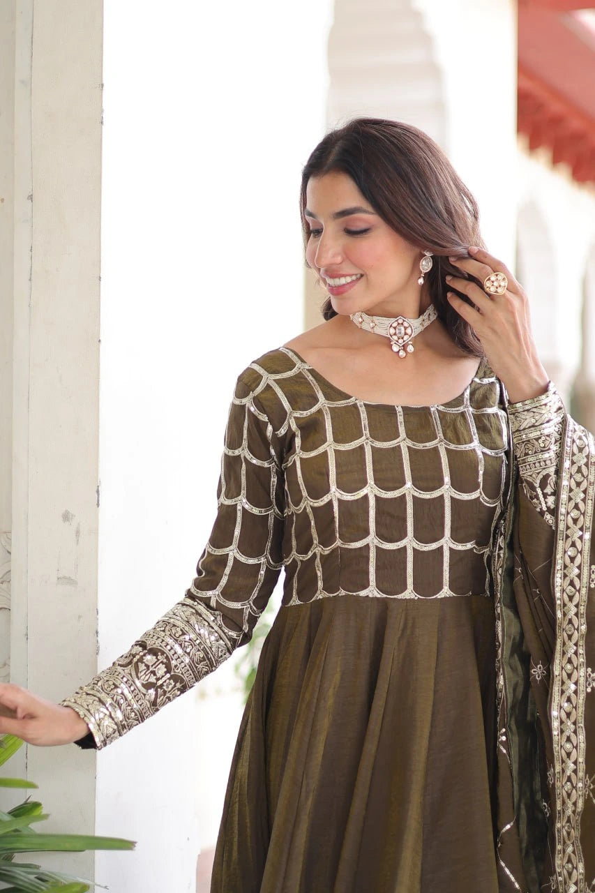 Woman wearing a traditional outfit with intricate patterns indoors.