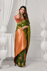 Woman wearing a green and orange saree in a white room