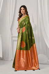 Woman wearing a green and orange saree with a white curtain background