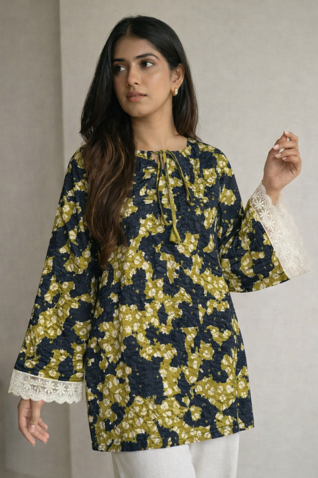 Woman wearing a floral patterned top with lace trim sleeves against a neutral background
