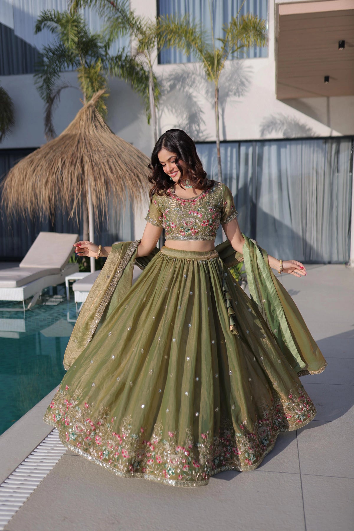 Woman in a green traditional outfit by a poolside
