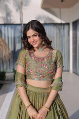 Woman in a green traditional outfit with floral patterns standing outdoors.