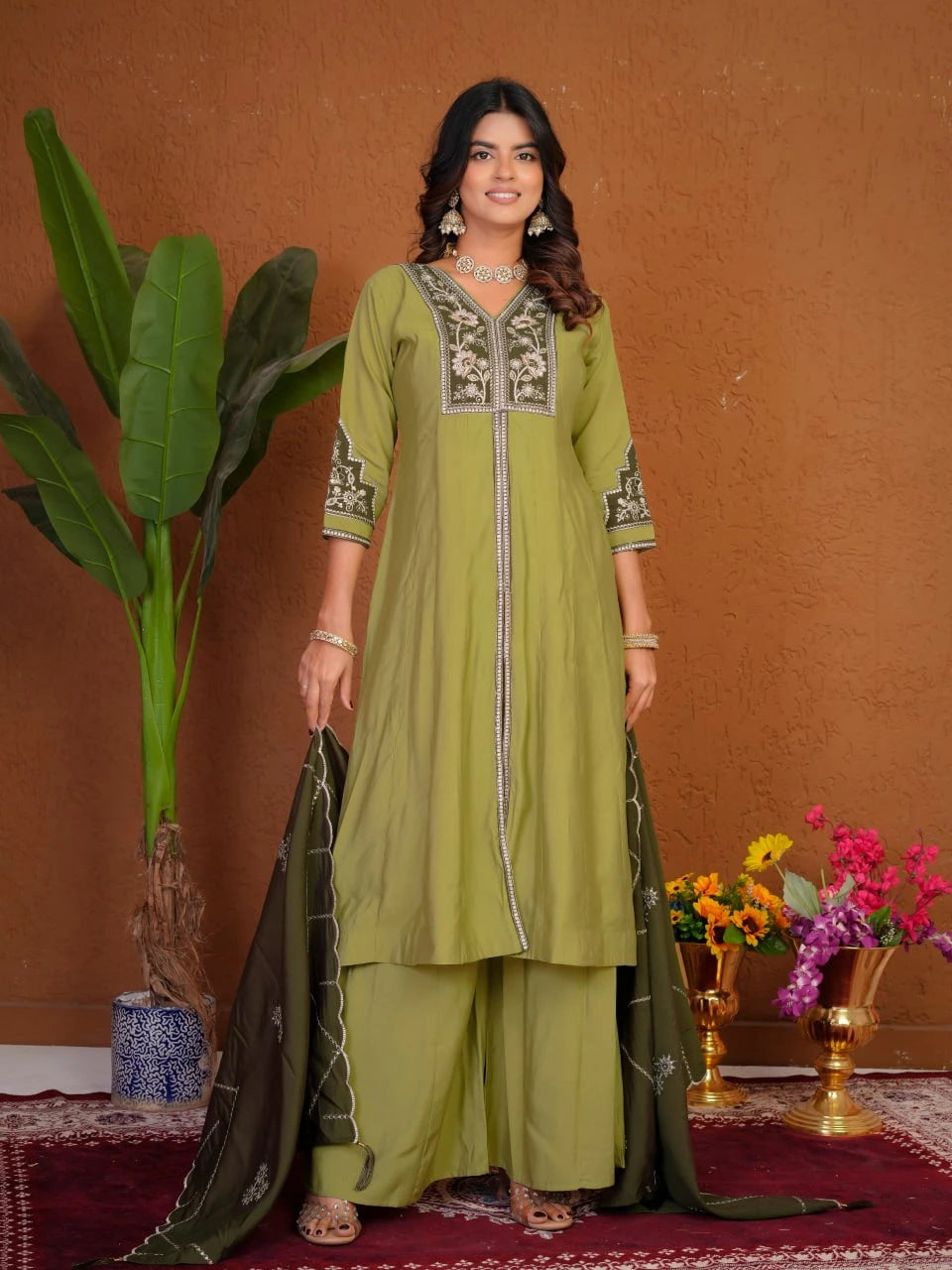 Woman in a green traditional outfit with floral decorations against a brown background