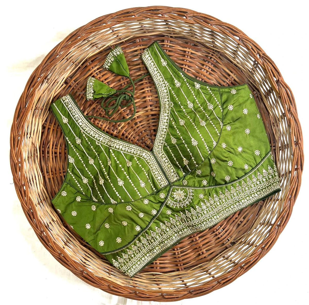 Green embroidered blouse with white patterns on a woven basket