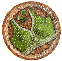 Green embroidered blouse with white patterns on a woven basket