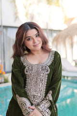 Woman in a green traditional outfit with intricate white embroidery by a pool