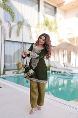 Woman in a green outfit standing by a pool with a modern building and plants in the background