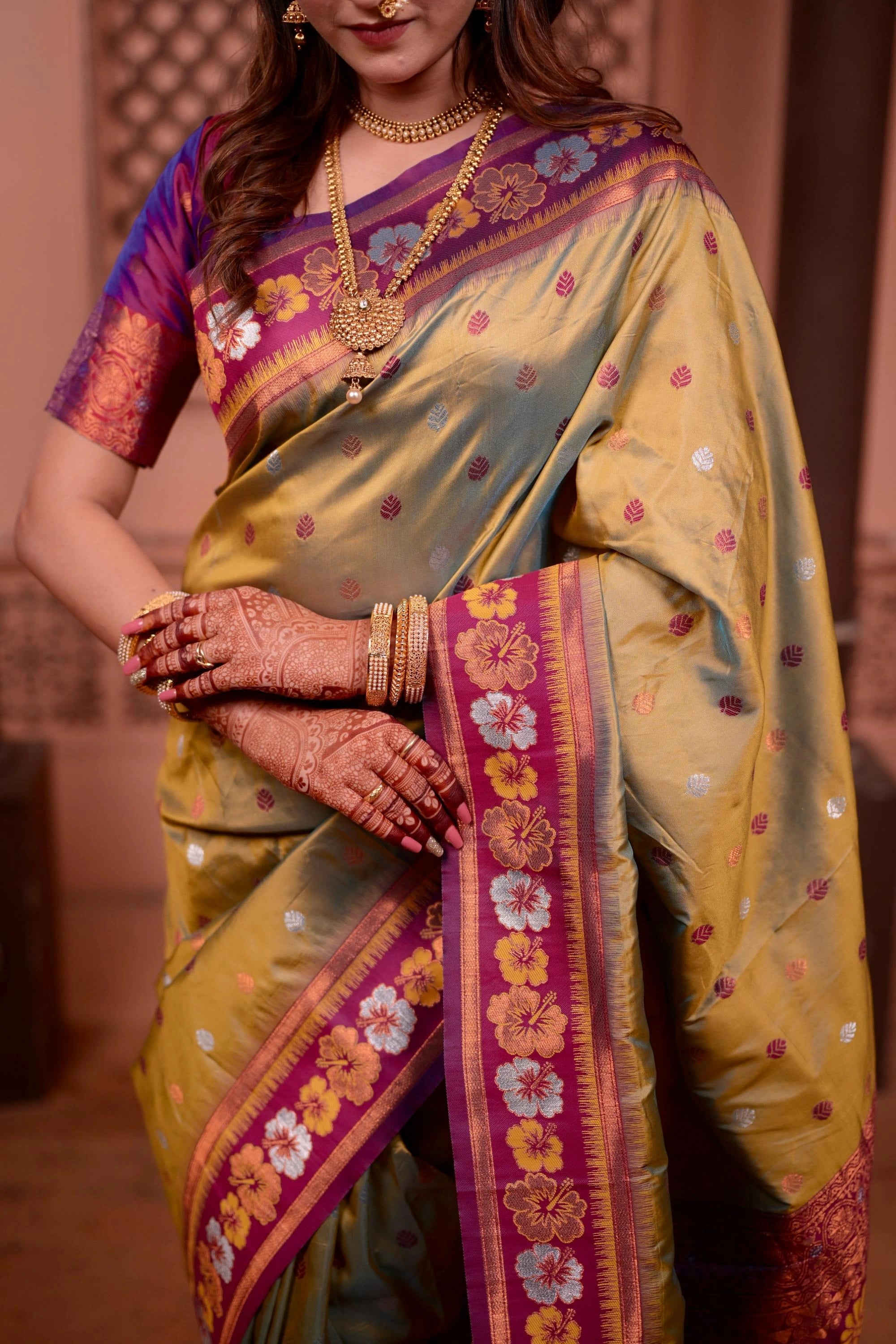 Woman wearing a traditional saree with floral patterns and jewelry.