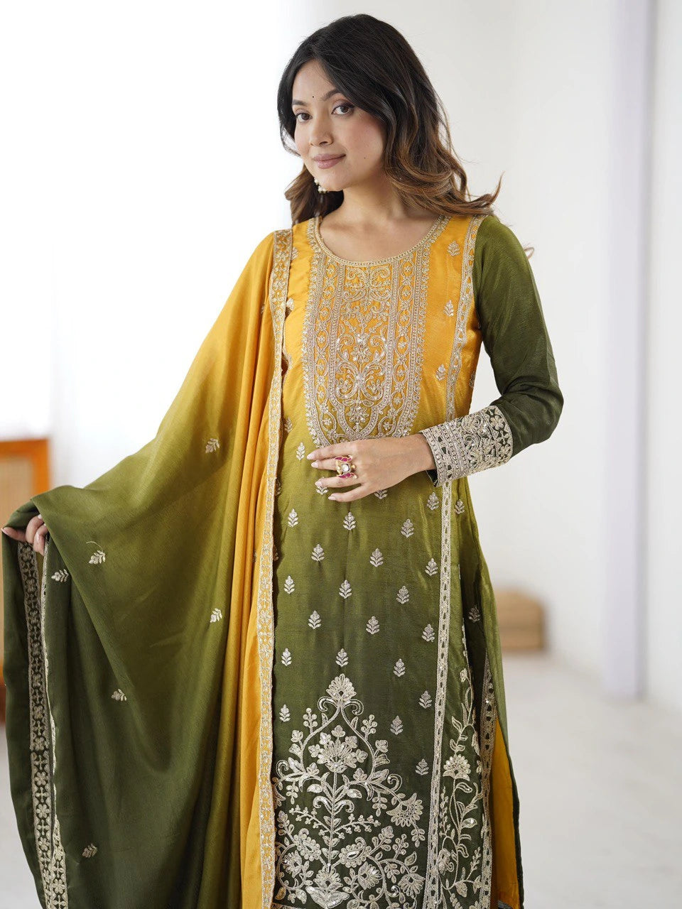 Woman wearing a green and yellow traditional outfit with floral patterns.