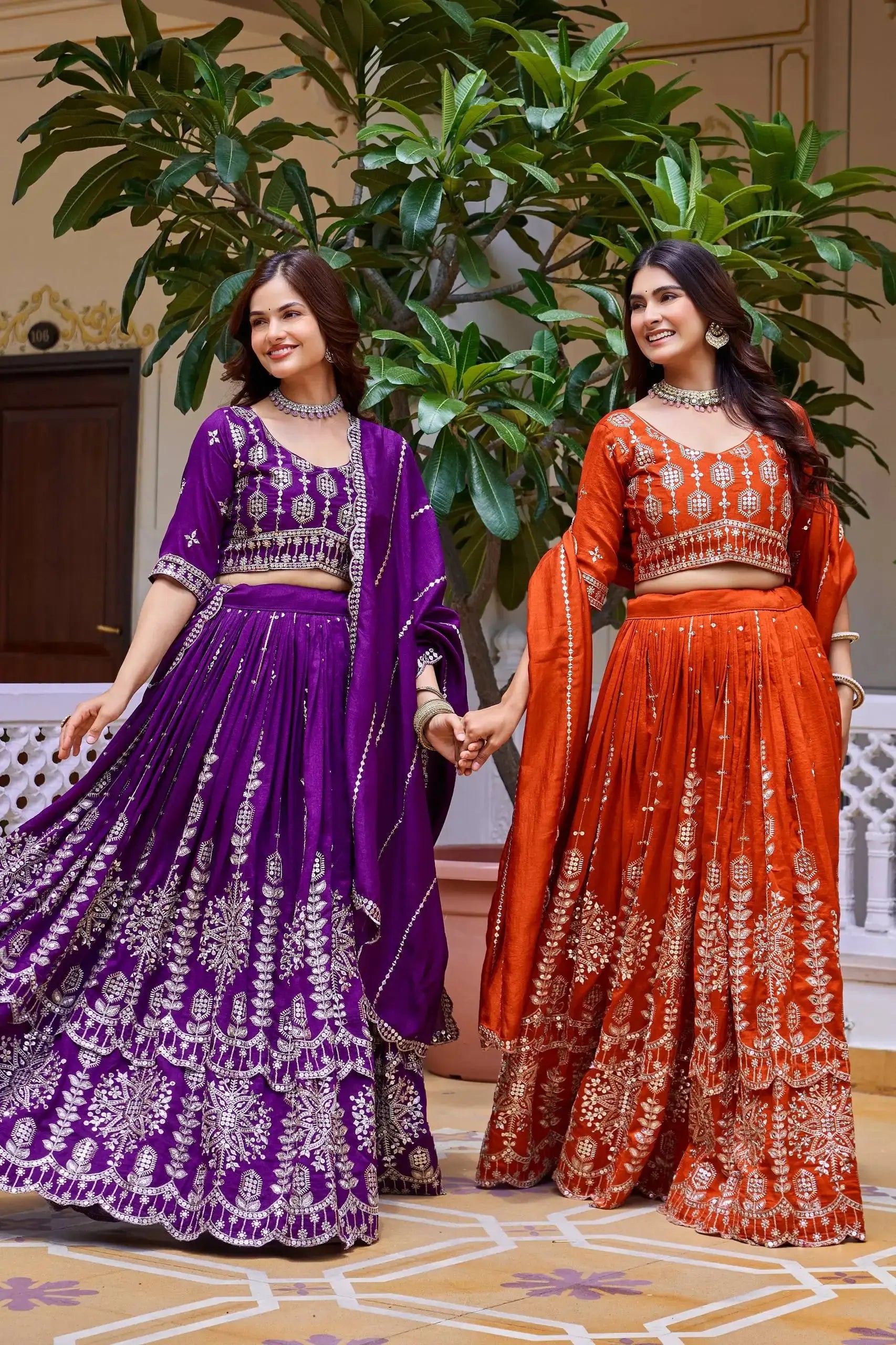 Lifestyle shot of orange and purple sequins embroidered lehengas worn together in festive setting