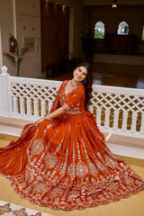 Seated view of orange vichitra lehenga showing full sequins embroidered skirt spread and border