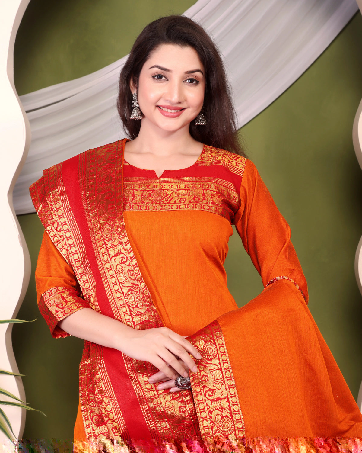 Woman wearing a traditional orange and red saree with a green background