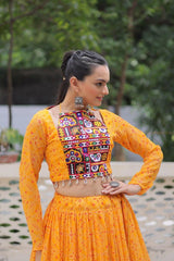Woman wearing a traditional orange outfit with a colorful embroidered blouse outdoors.