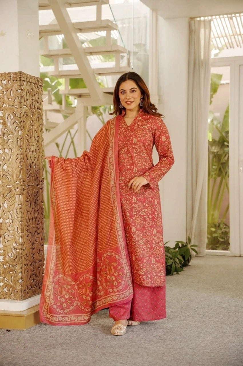 Woman wearing a traditional pink and red outfit with a matching dupatta in a well-lit room.