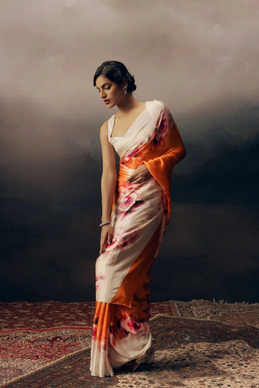 Woman in a floral saree with an orange and beige pattern against a dark background