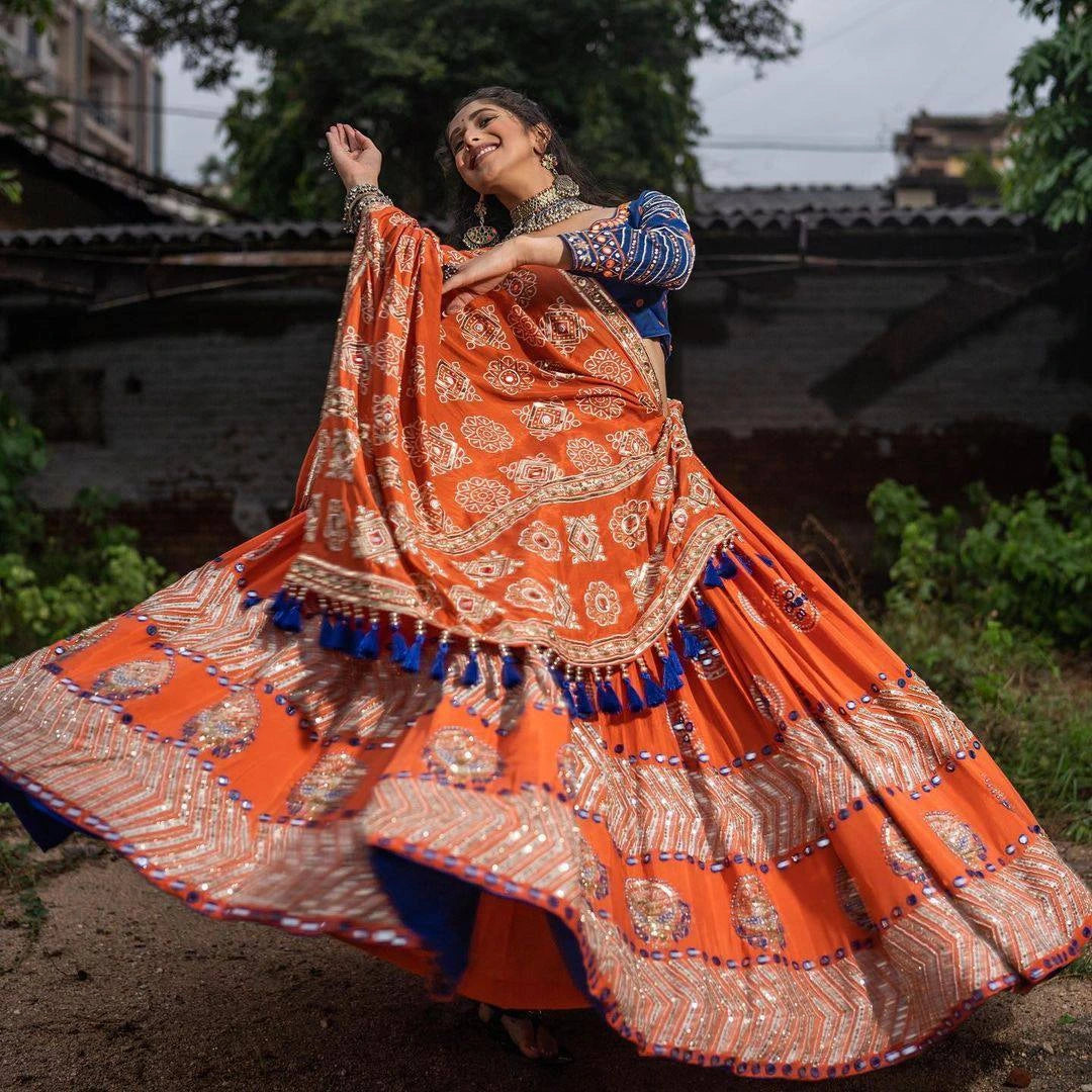 Woman in an orange and blue traditional outfit with a flowing skirt outdoors.