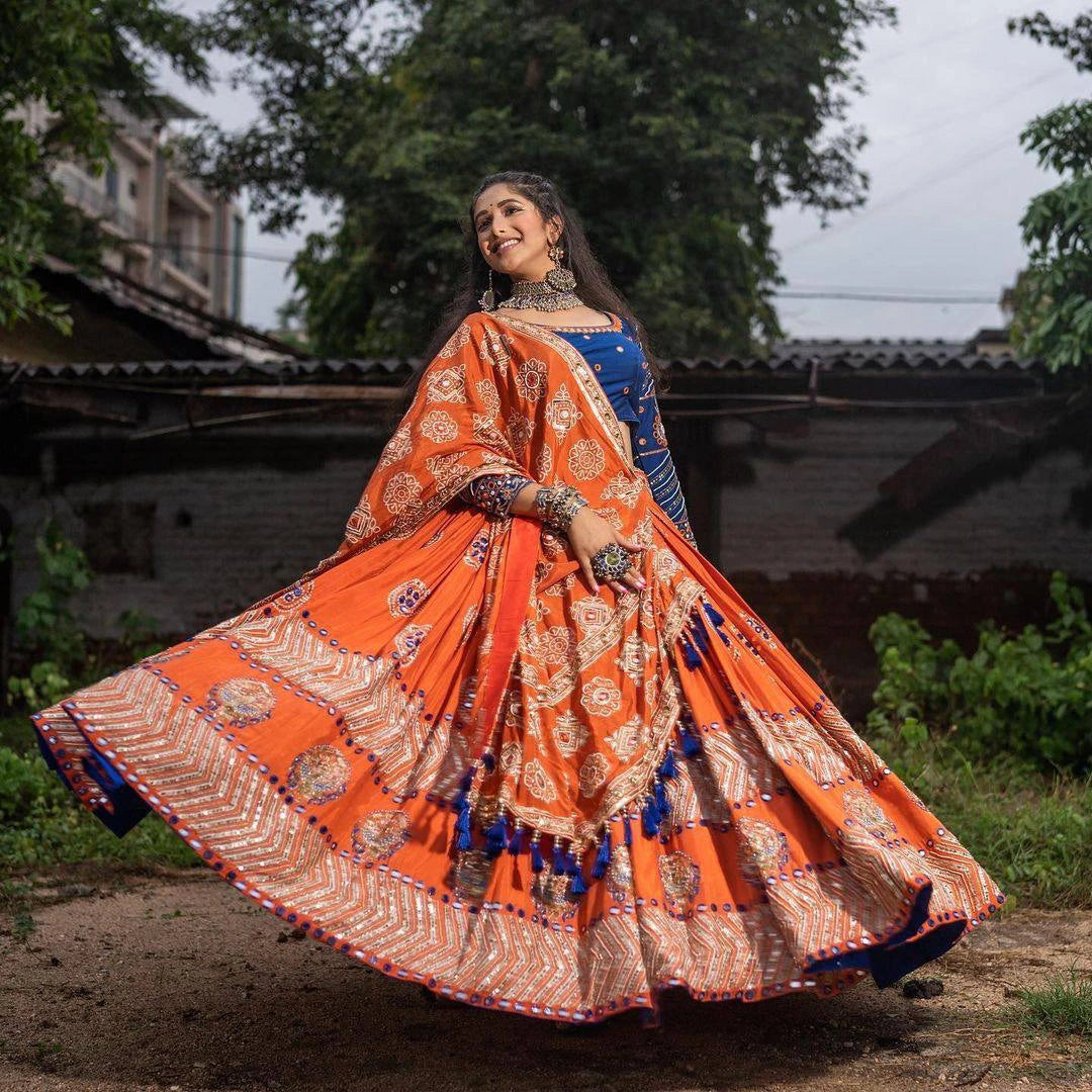 Woman in an orange and blue traditional outfit with a flowing skirt outdoors.