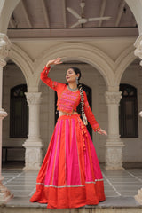 Woman in traditional bright orange and pink outfit standing in an architectural setting.
