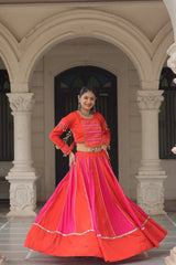 Woman in a traditional red and pink outfit standing in front of an archway.