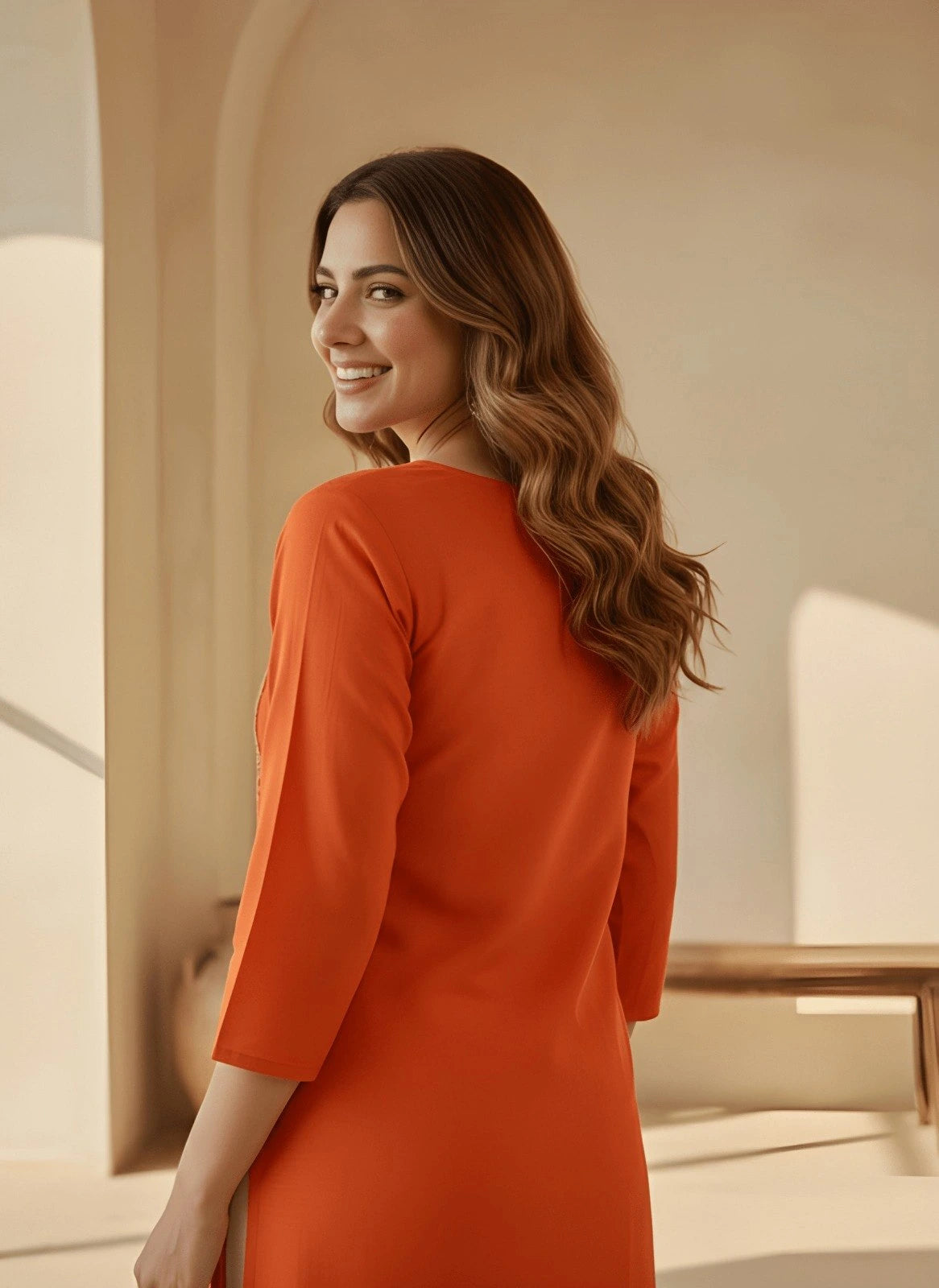 Woman in an orange dress standing in a softly lit room.