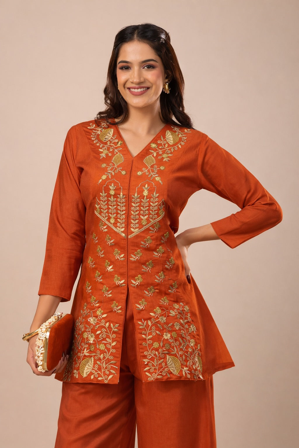 Woman wearing an orange embroidered traditional outfit on a beige background