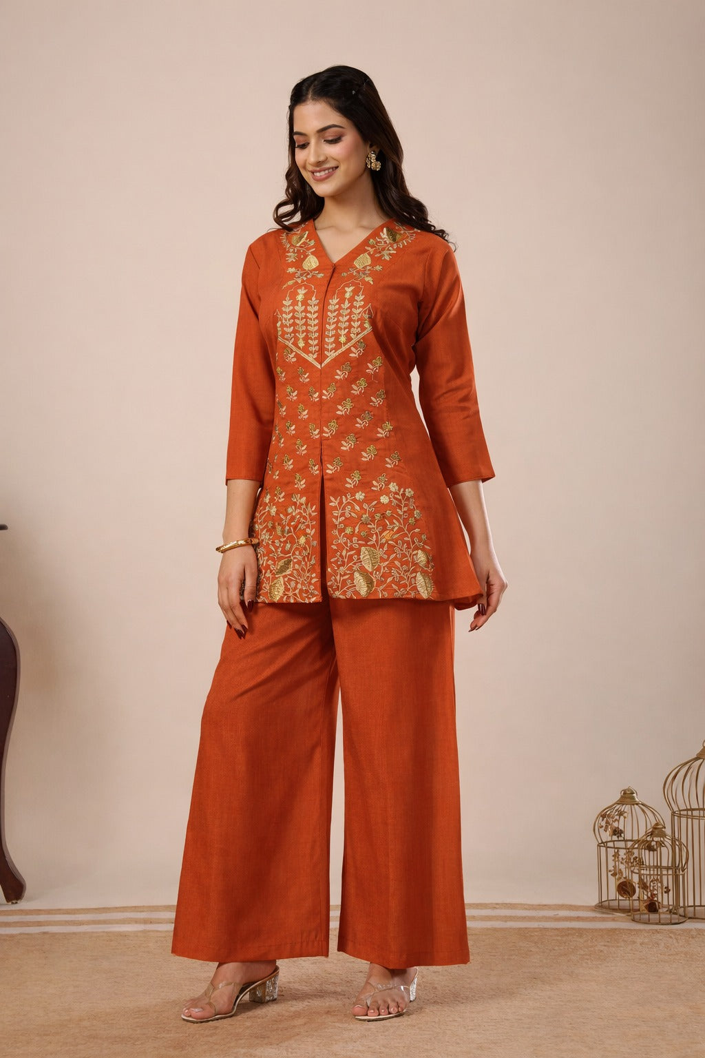 Woman wearing an orange traditional outfit with intricate patterns on a beige background