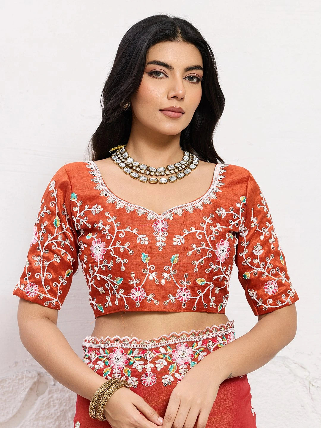 Woman wearing a red embroidered blouse with white patterns on a white background