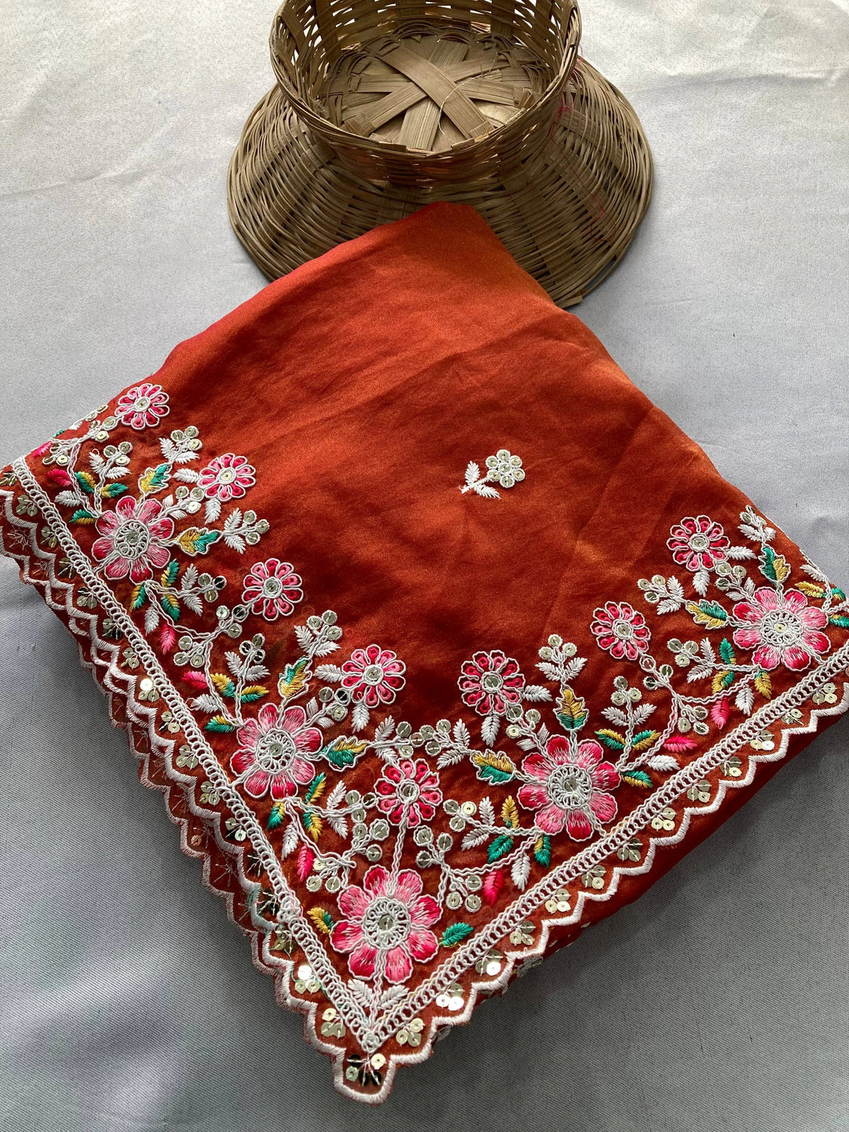 Red embroidered fabric with floral patterns on a light gray background